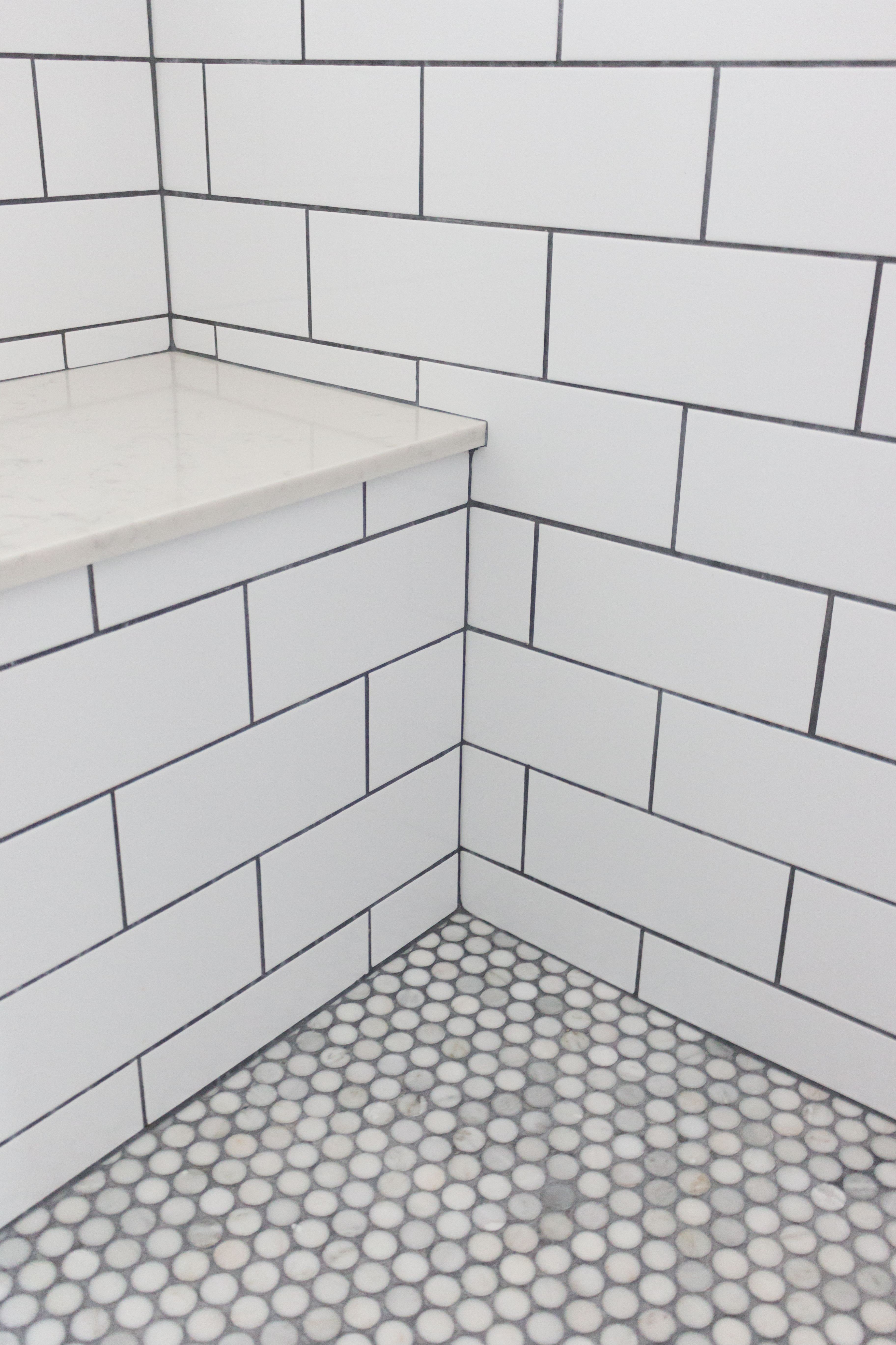 master bathroom shower subway tile with grey grout stone bench and penny round tiles
