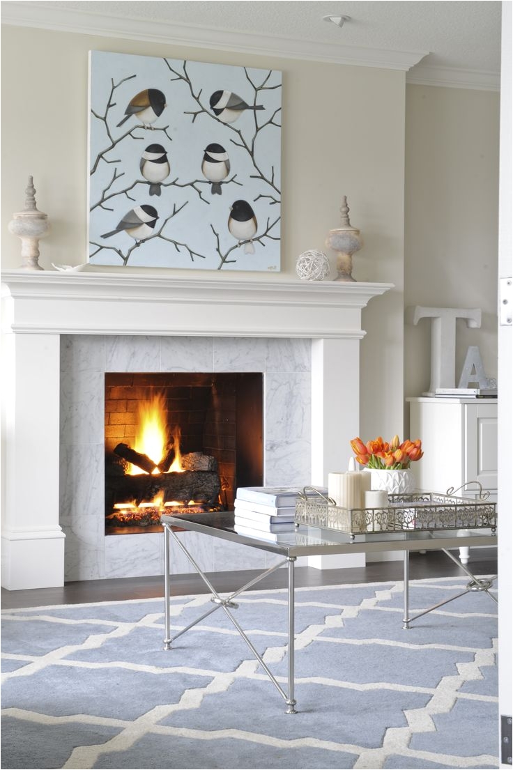 living room designed by enviable designs this fireplace is tiled with a carrera marble surround and white mantle upon which perches a whimsical style