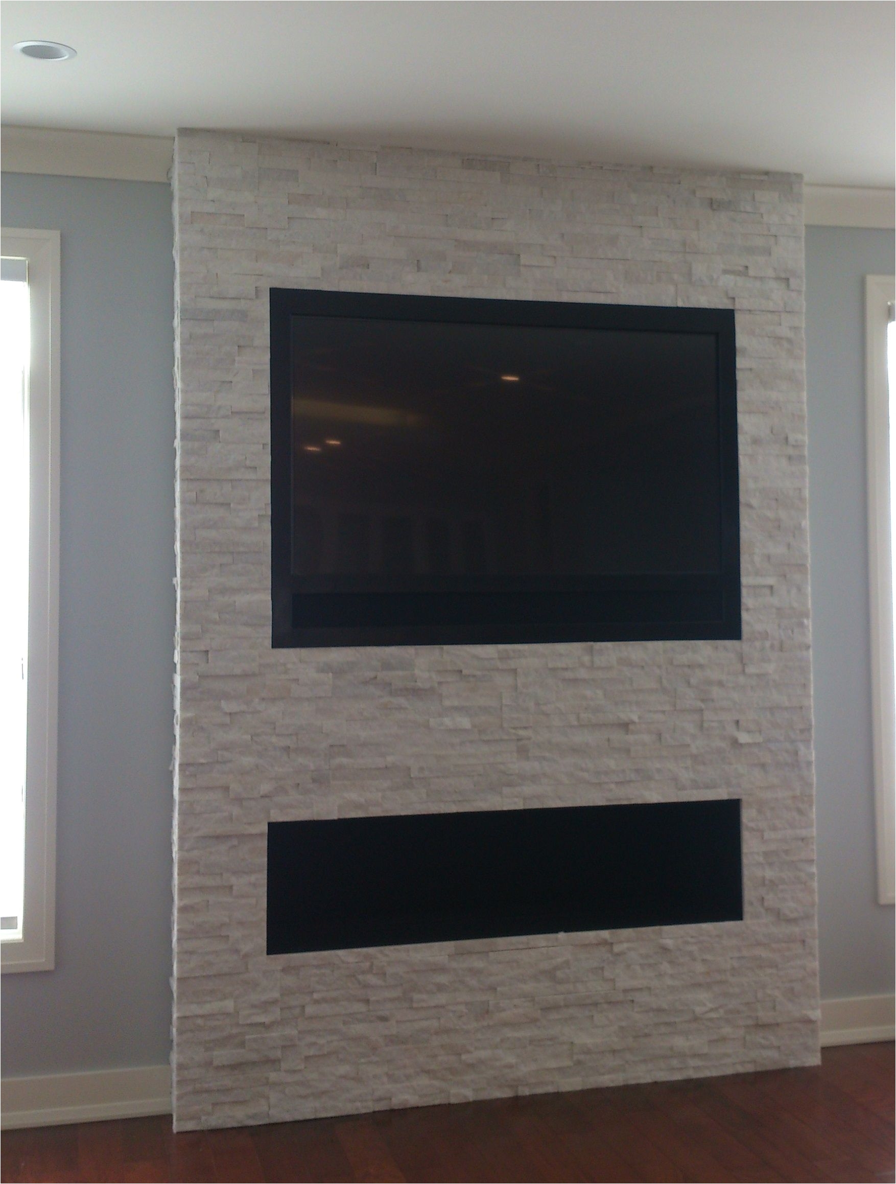 wondering how to mount a tv over a fireplace without a mantel we inset a 60 lg tv and three speakers above a fireplace on a stone wall and surrounded it