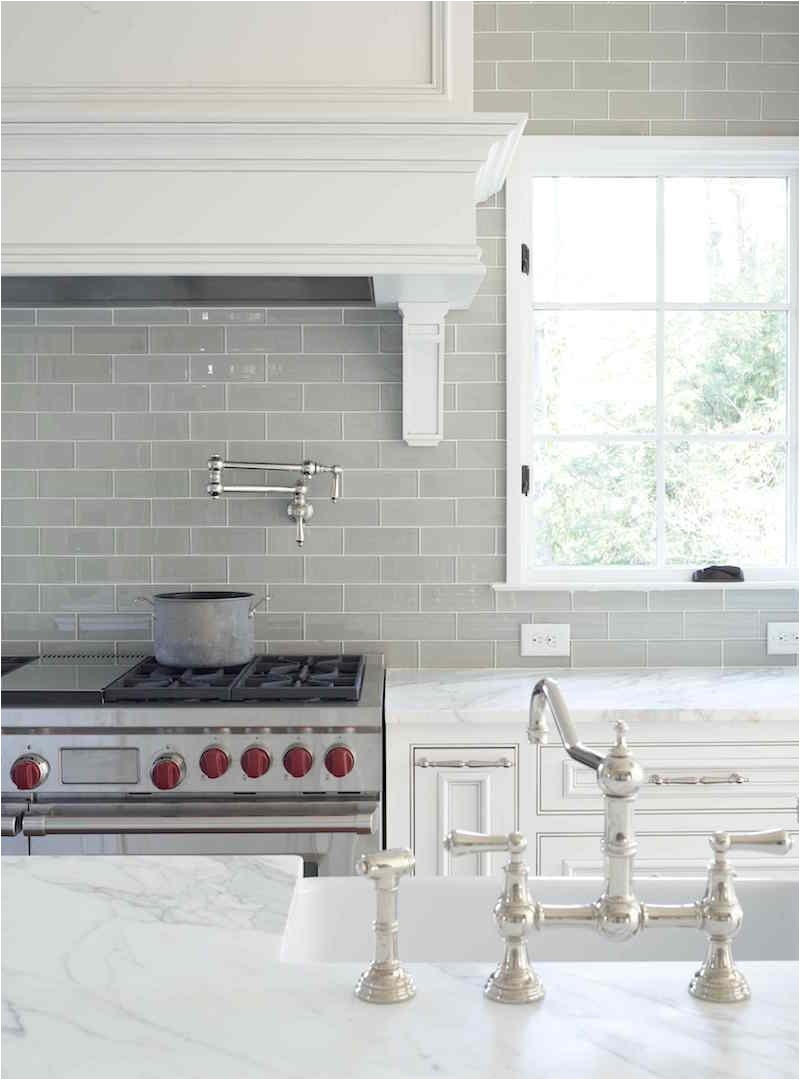 gray glass kitchen backsplash with carrera marble counters in a pretty traditional white kitchen nickel faucet and wolf range