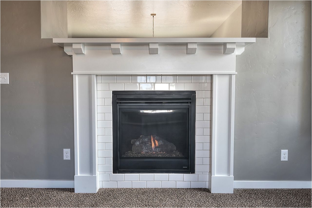 cozy up to this fireplace surrounded with white subway tile and beautiful craftsman style mantel