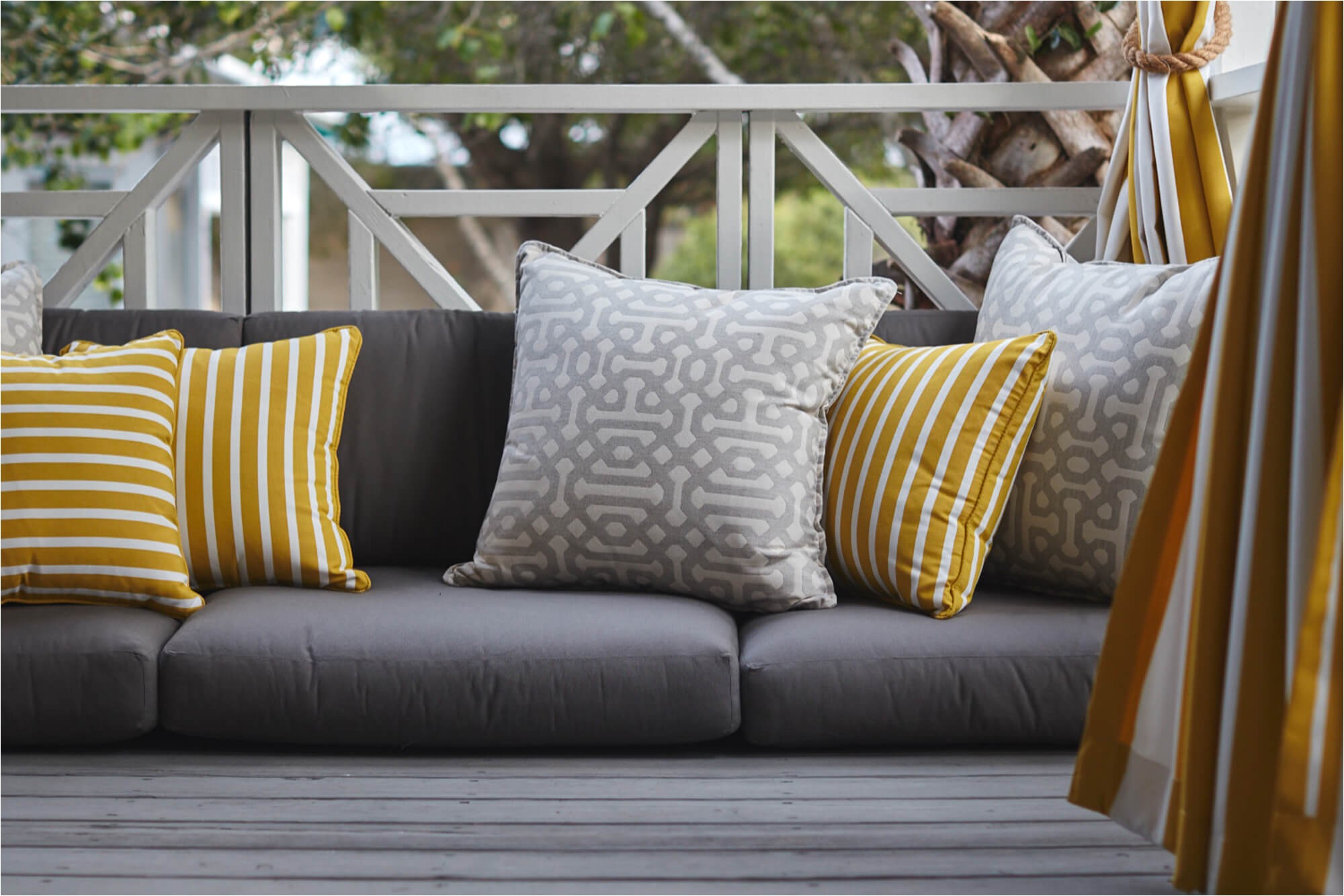 grey outdoor cushions with yellow and grey decorative pillows and yellow drapery outdoor sofa