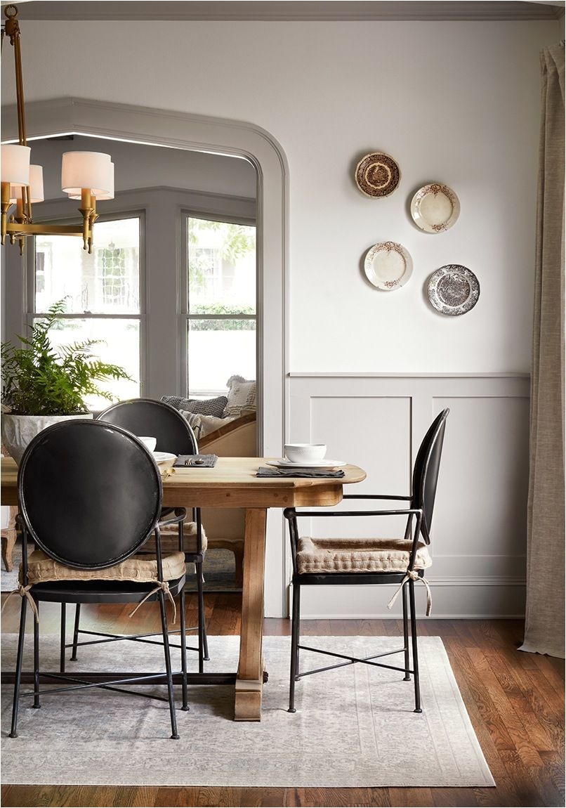 classic decor inspiration in this dining room with light grey painted wainscot gothic archway plates on the wall and modern dining chairs