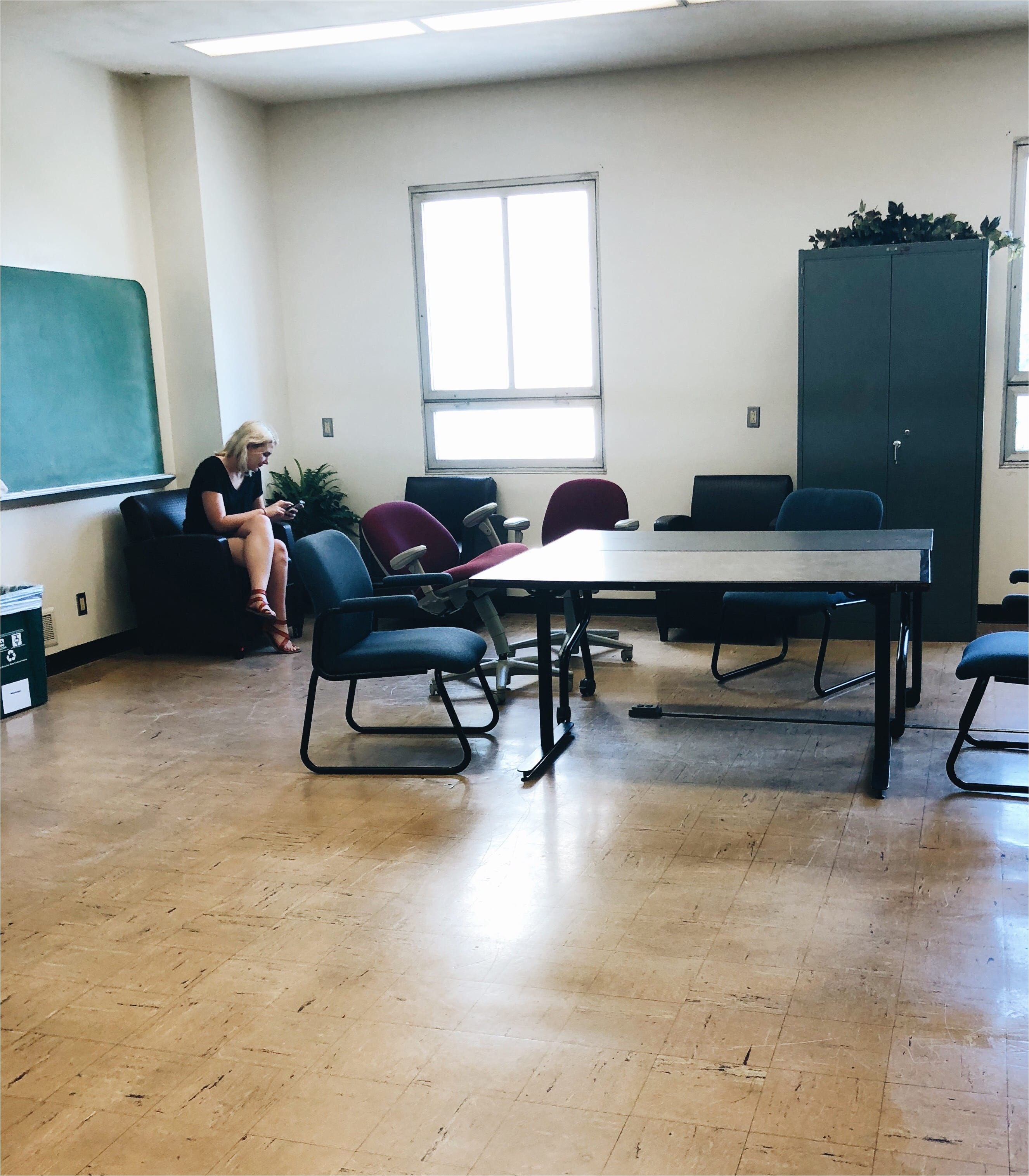 brenna sits in an armchair against the left wall nearby two tables are surrounded