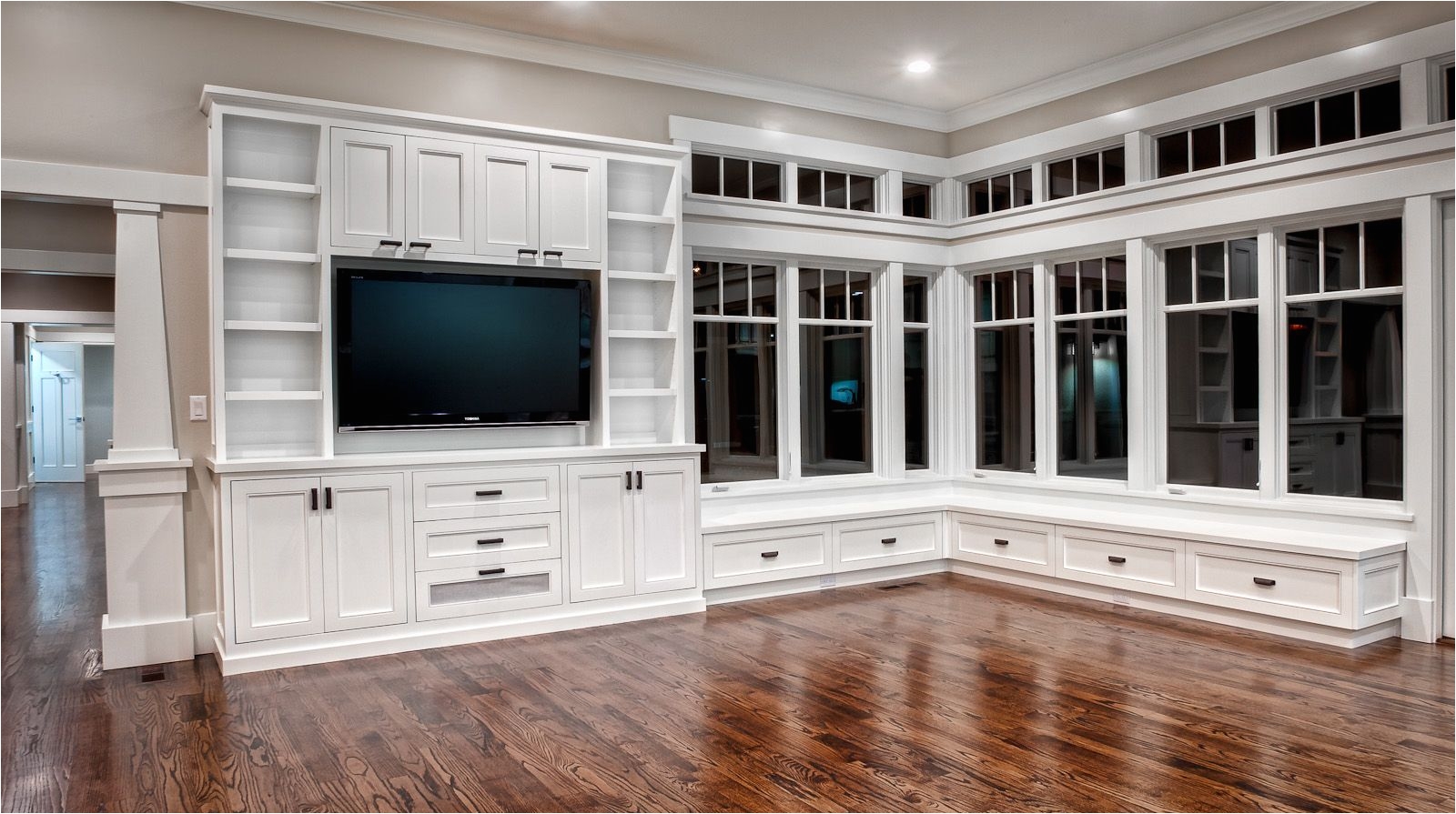 gorgeous custom entertainment center bookcases and built in window seat with amazing windows and transoms above