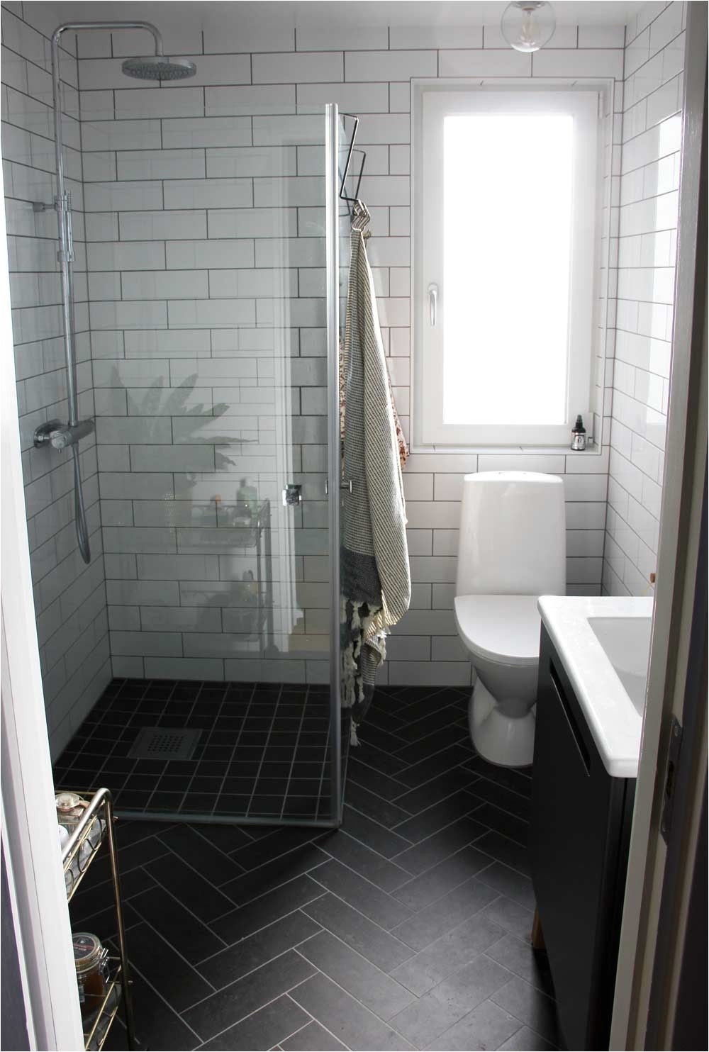 i love everything about this bathroom the black herringbone floor the white subway tiles with black grout and the frameless shower doors