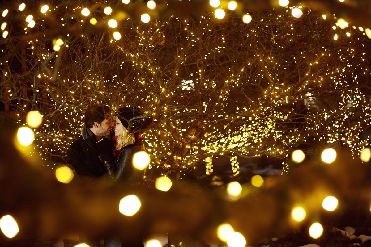 young couple kissing surrounded by city christmas lights
