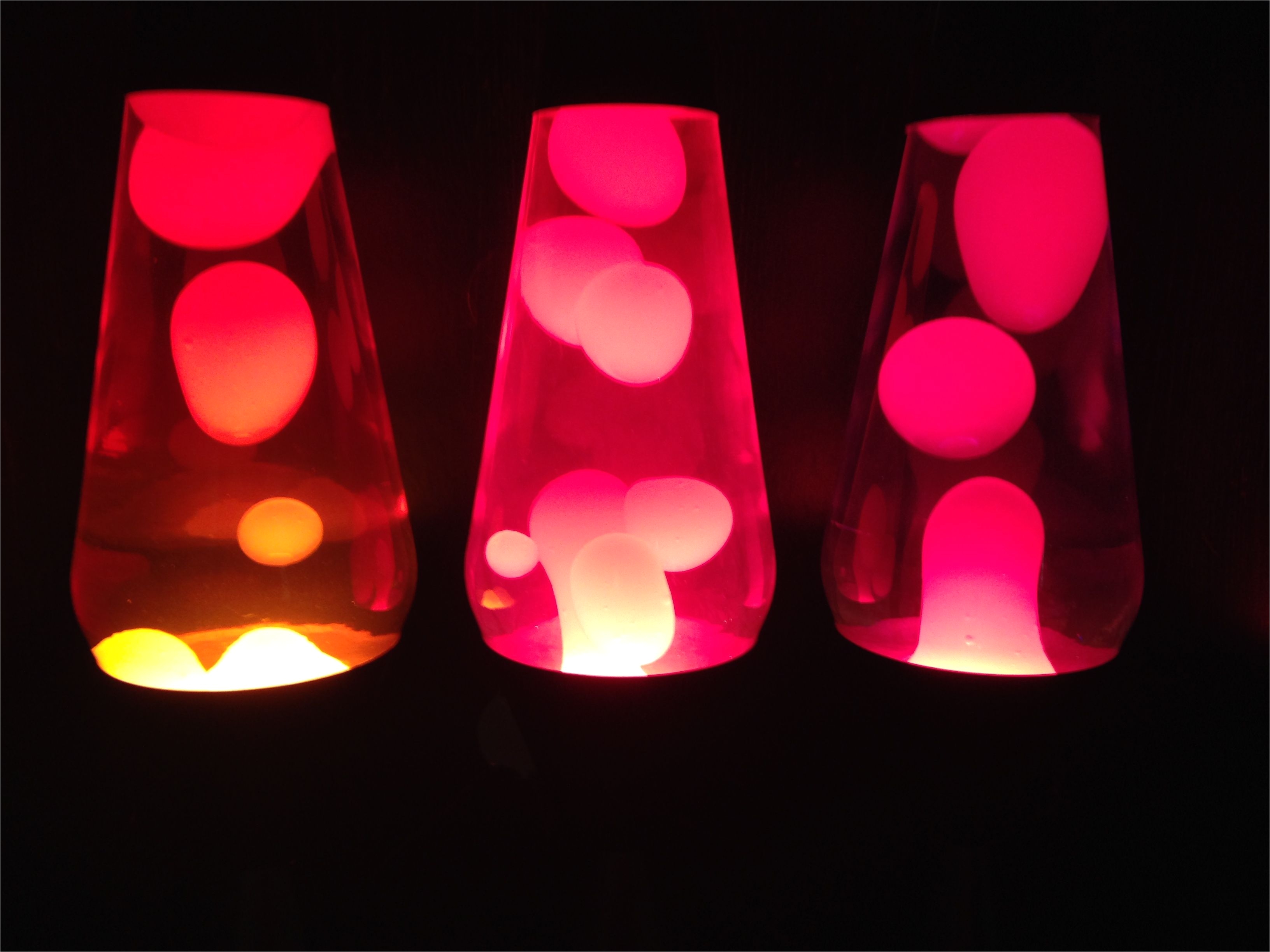 three premier lava lamps one with yellow wax and red liquid one with white wax and pink liquid and one with yellow wax and purple liquid