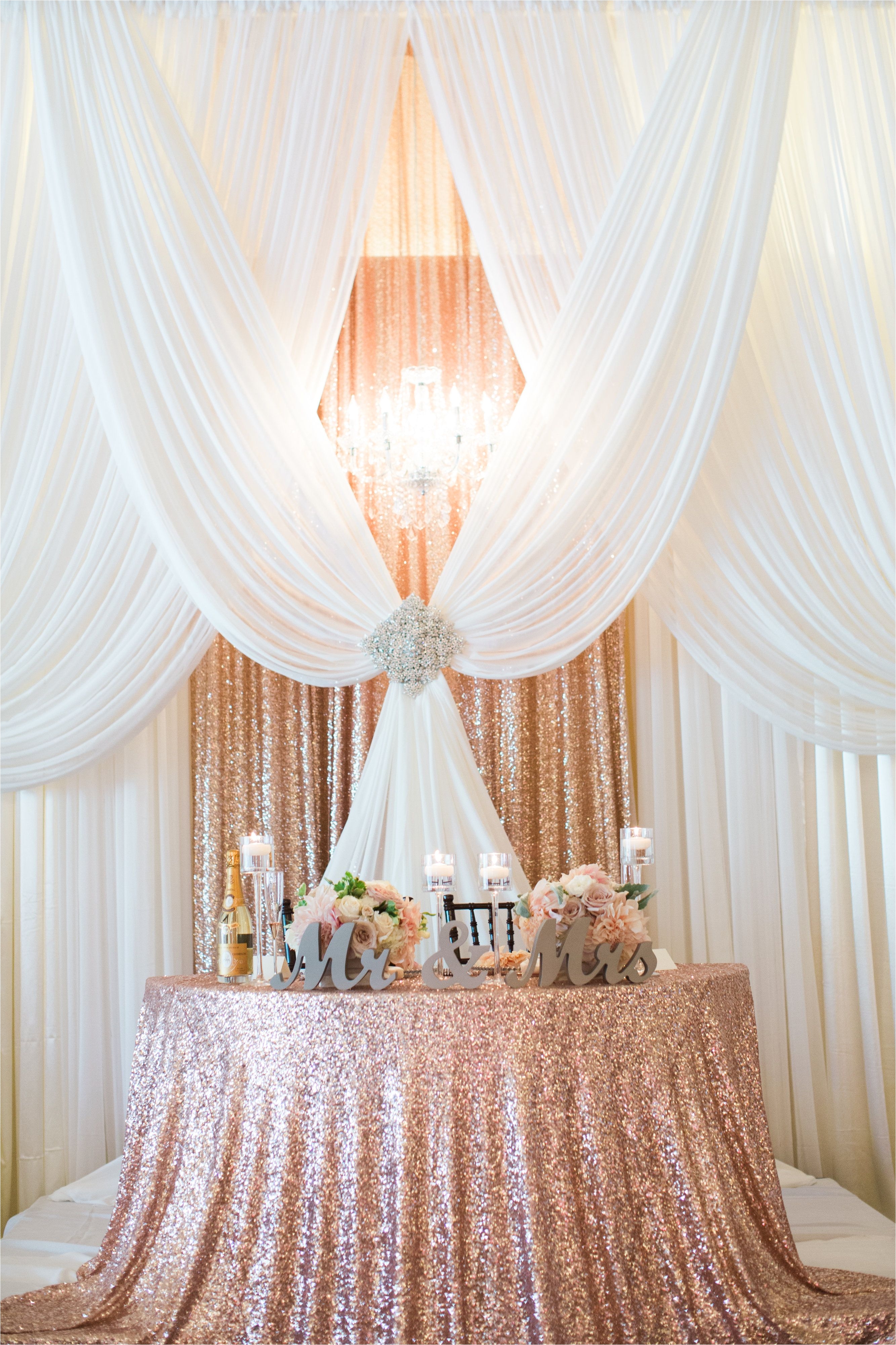gorgeous pipe and drape backdrop to a half moon sweetheart table in sequin rose gold love