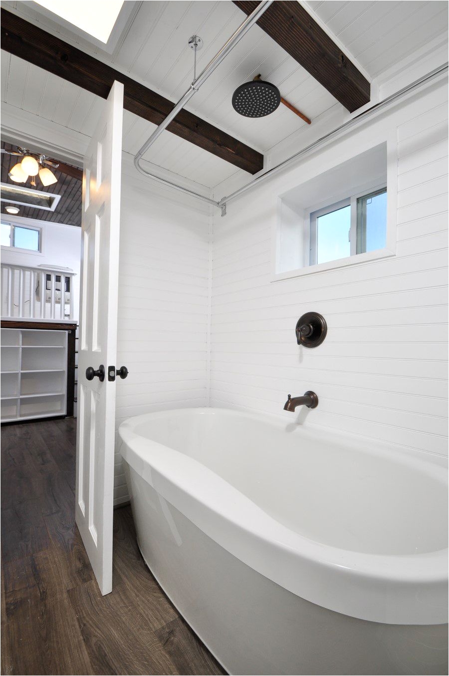 past the kitchen is the luxurious bathroom with oval soaking tub and rain shower head sink and vanity and composting toilet