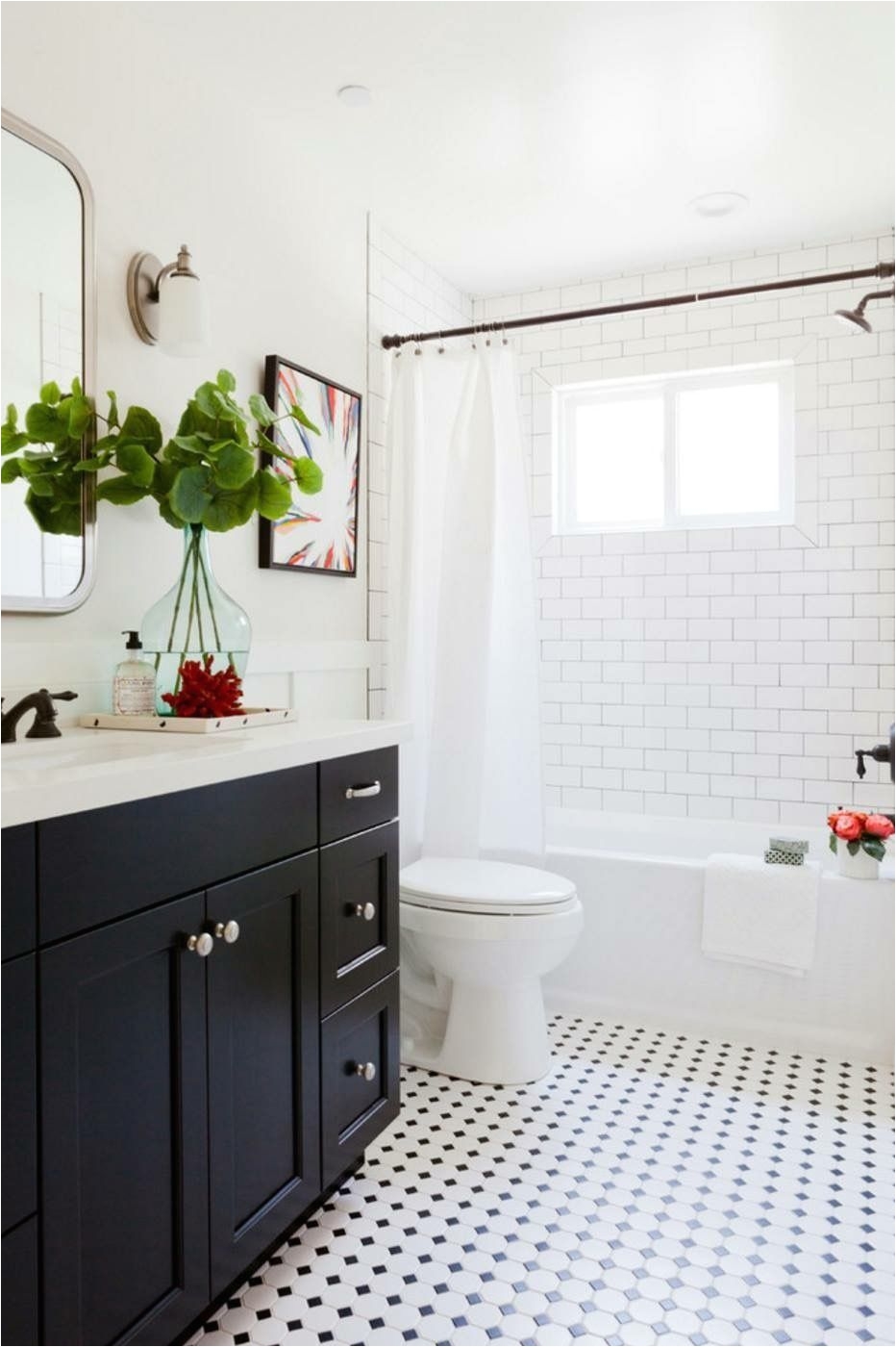 Love how fresh and modern this bathroom feels while still highlighting timeless styles like black tuxedo cabinets white subway tiled walls and checkered