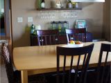 Dining Room Table with Wine Rack Underneath Floating Shelves Above A Bar Set Up Hanging Glasses Wine Fridge